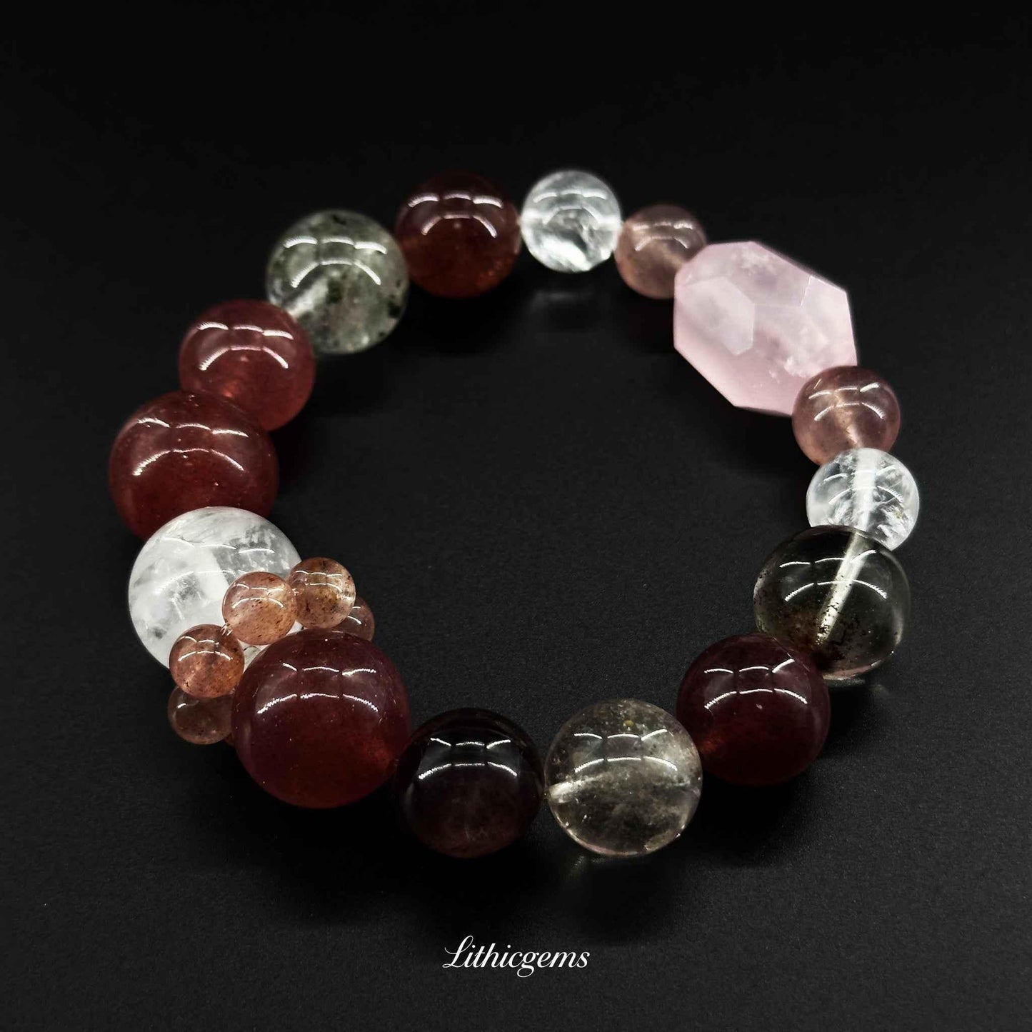 Natural crystal gemstone beaded bracelet with pink, red, and clear stones on black background