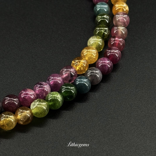 Close-up of polished multicolored natural gemstone beads on black background from Lithicgems