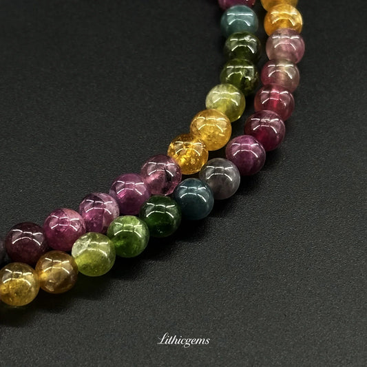 Close-up of polished multicolored natural gemstone beads on black background from Lithicgems