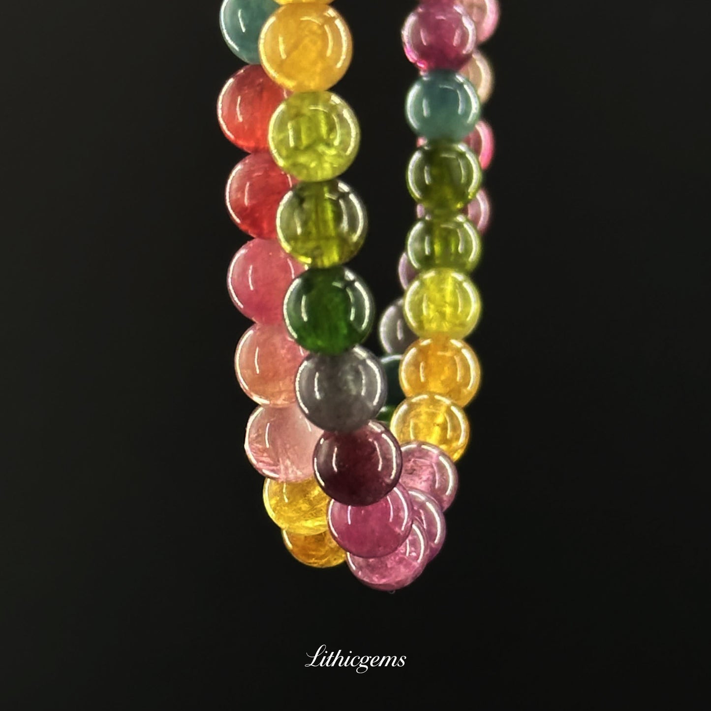 Close-up of multicolored natural crystal gemstone beads bracelet with polished round stones on black background