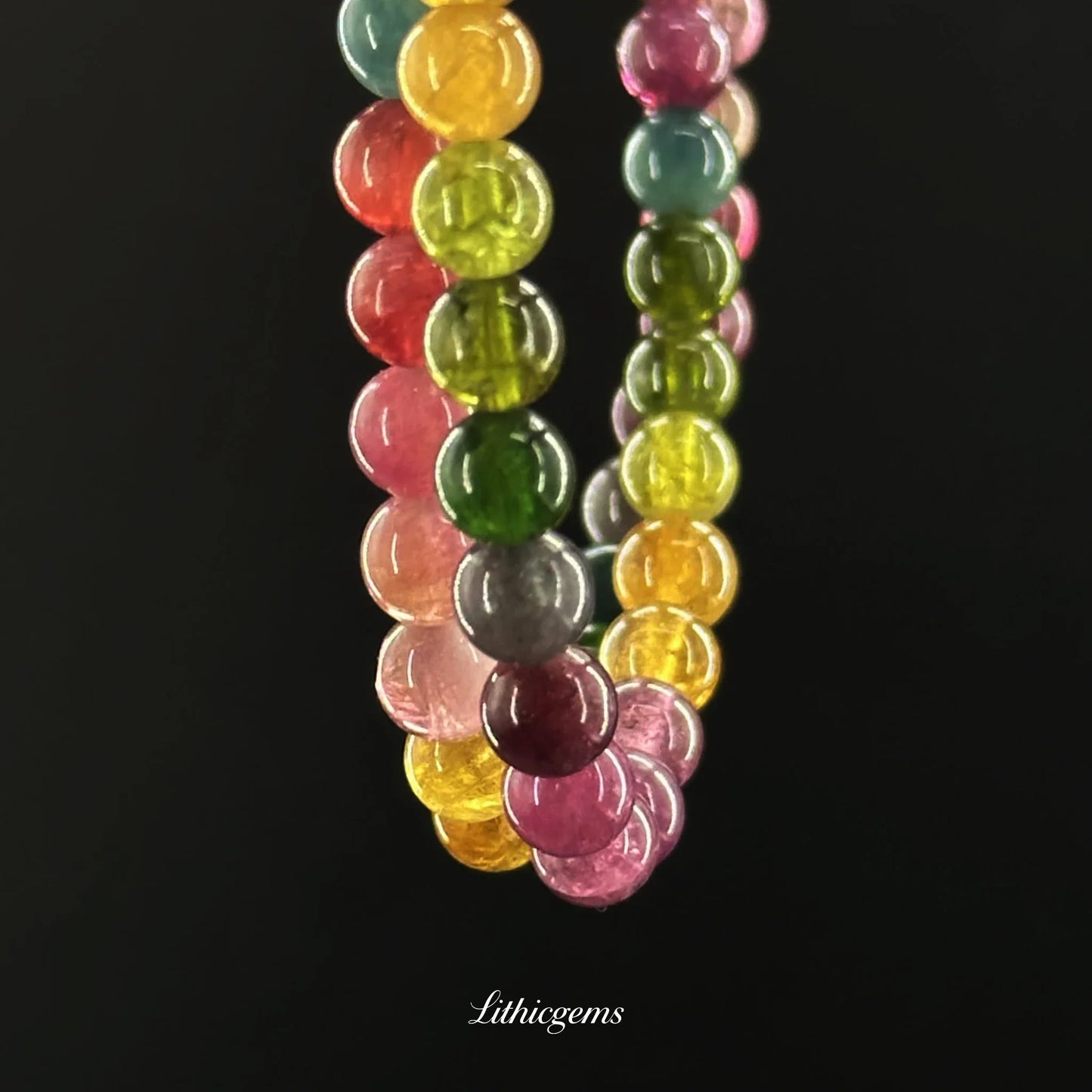 Close-up of multicolored natural crystal gemstone beads bracelet with polished round stones on black background