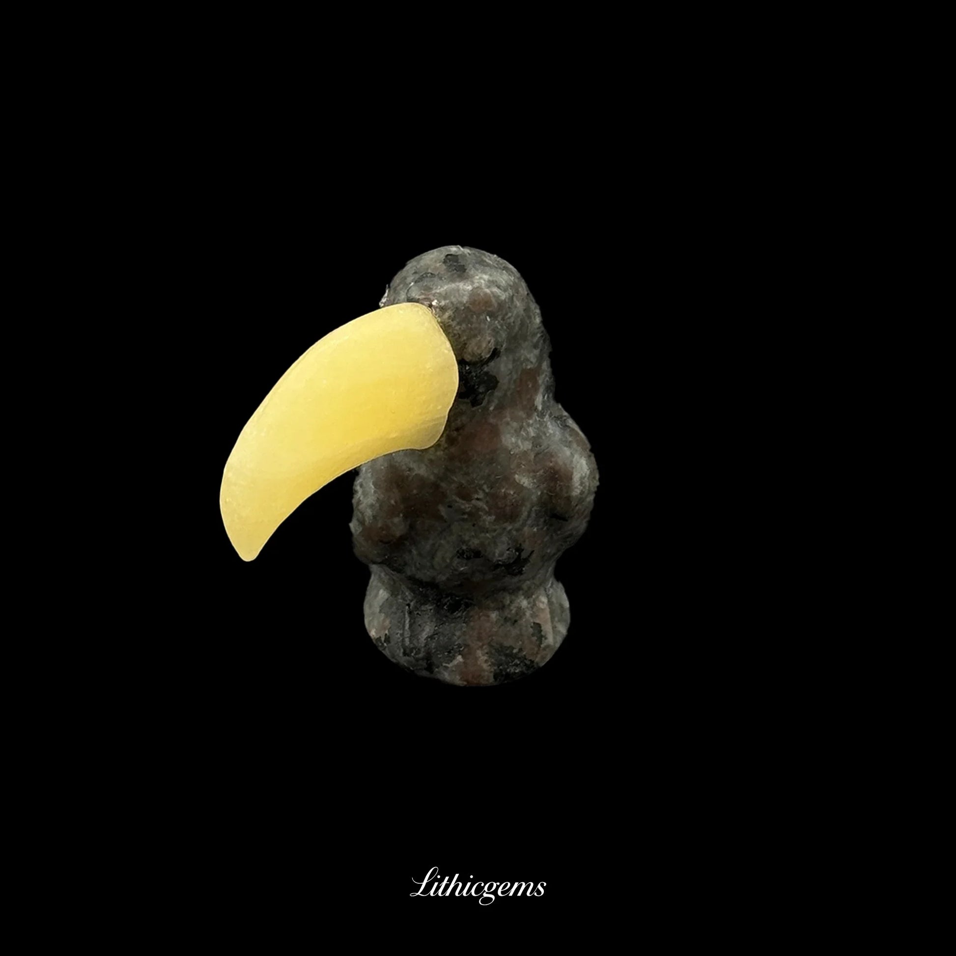 Natural crystal toucan figurine with yellow gemstone beak on black background, Lithicgems boutique