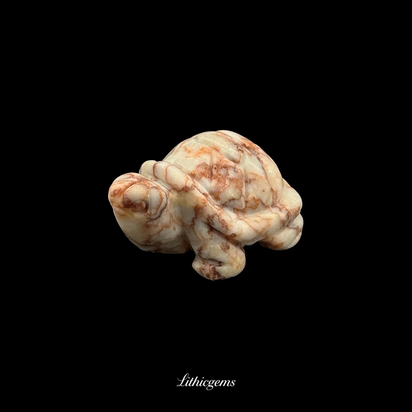 Natural gemstone turtle figurine with brown and cream marbling on black background, Lithicgems