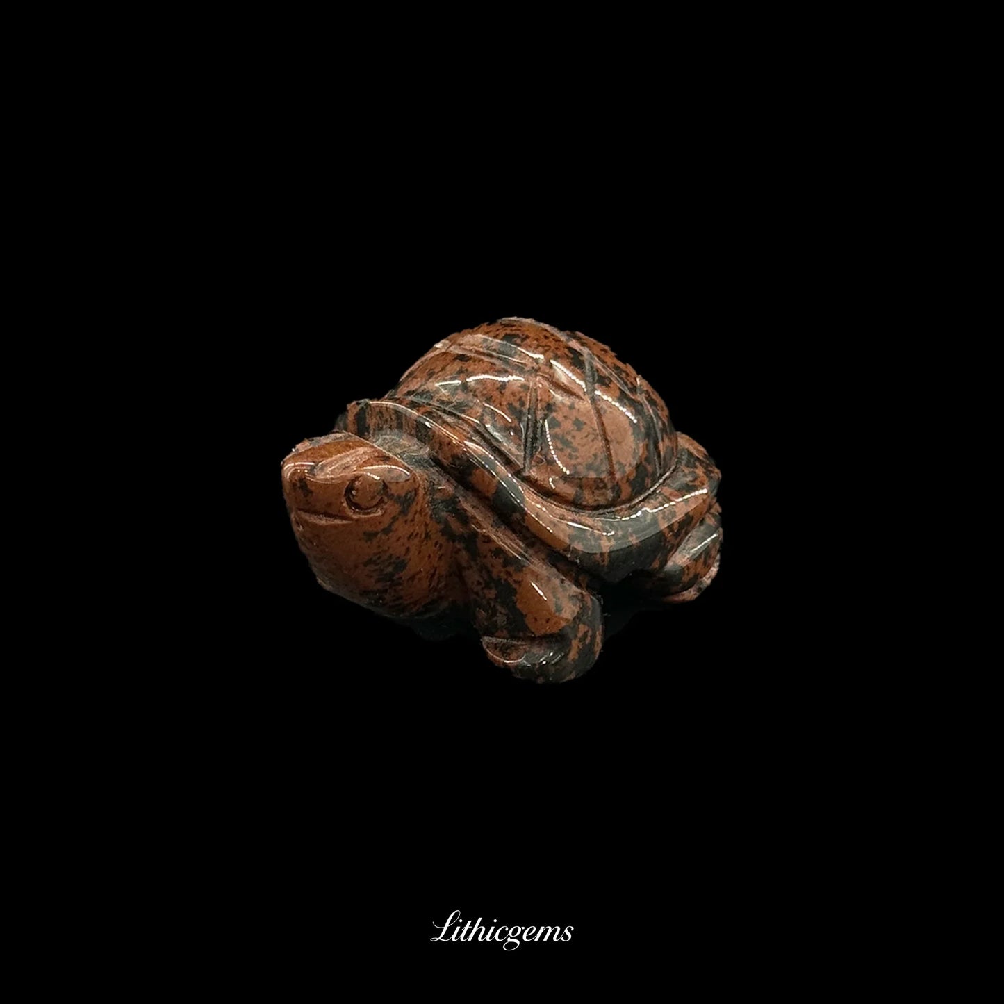 Polished natural gemstone turtle figurine with brown and black patterns on black background