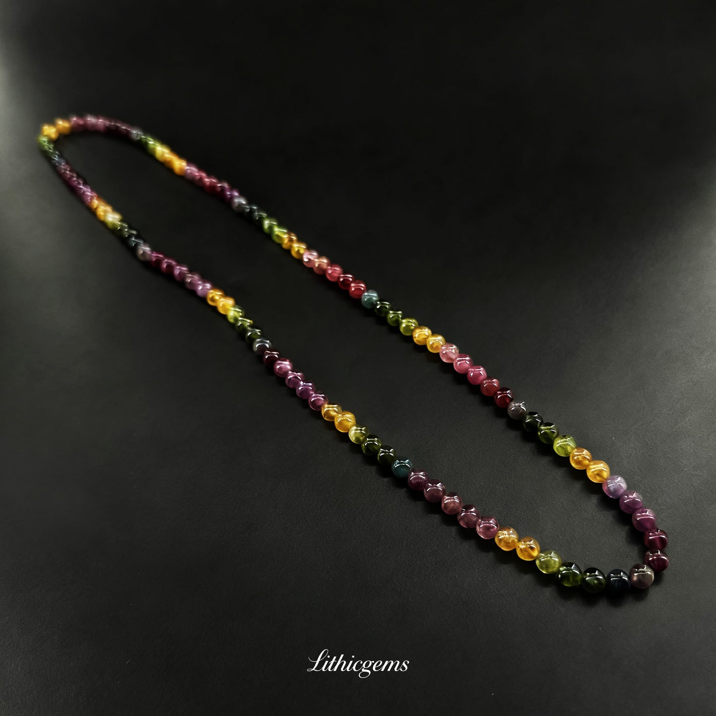 Multicolored natural crystal gemstone bead necklace on black background, premium healing jewelry