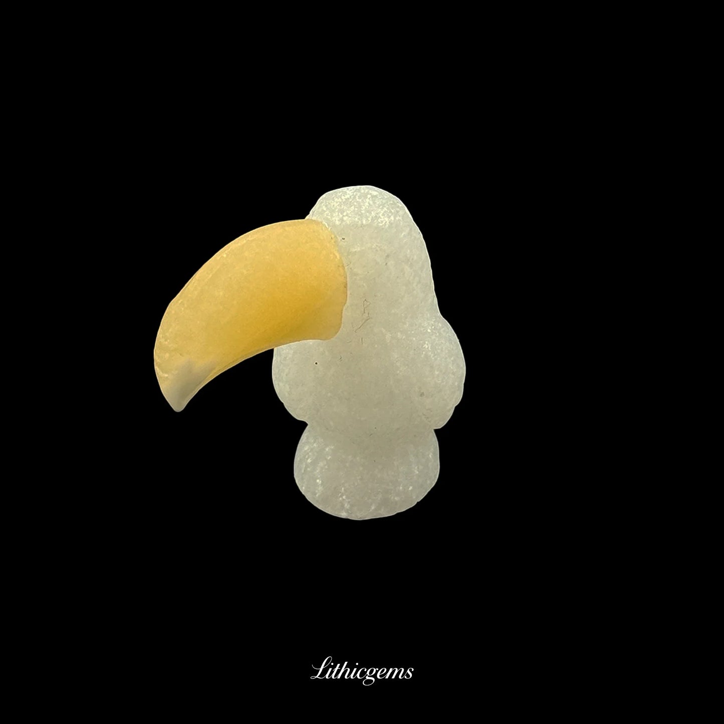 Carved gemstone toucan figurine with yellow beak on black, Lithicgems crystal boutique