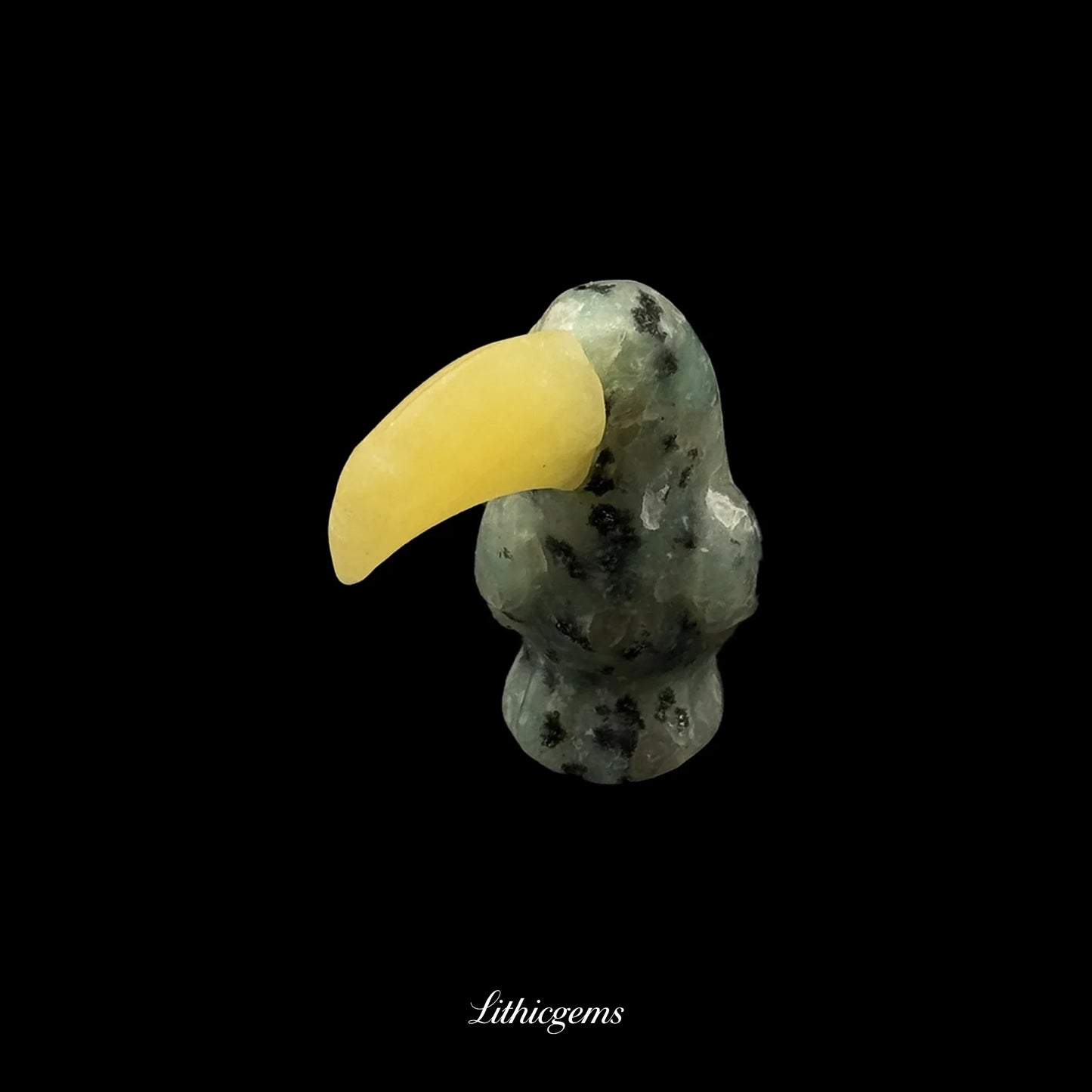 Hand-carved gemstone toucan figurine with yellow beak on black background, Lithicgems boutique