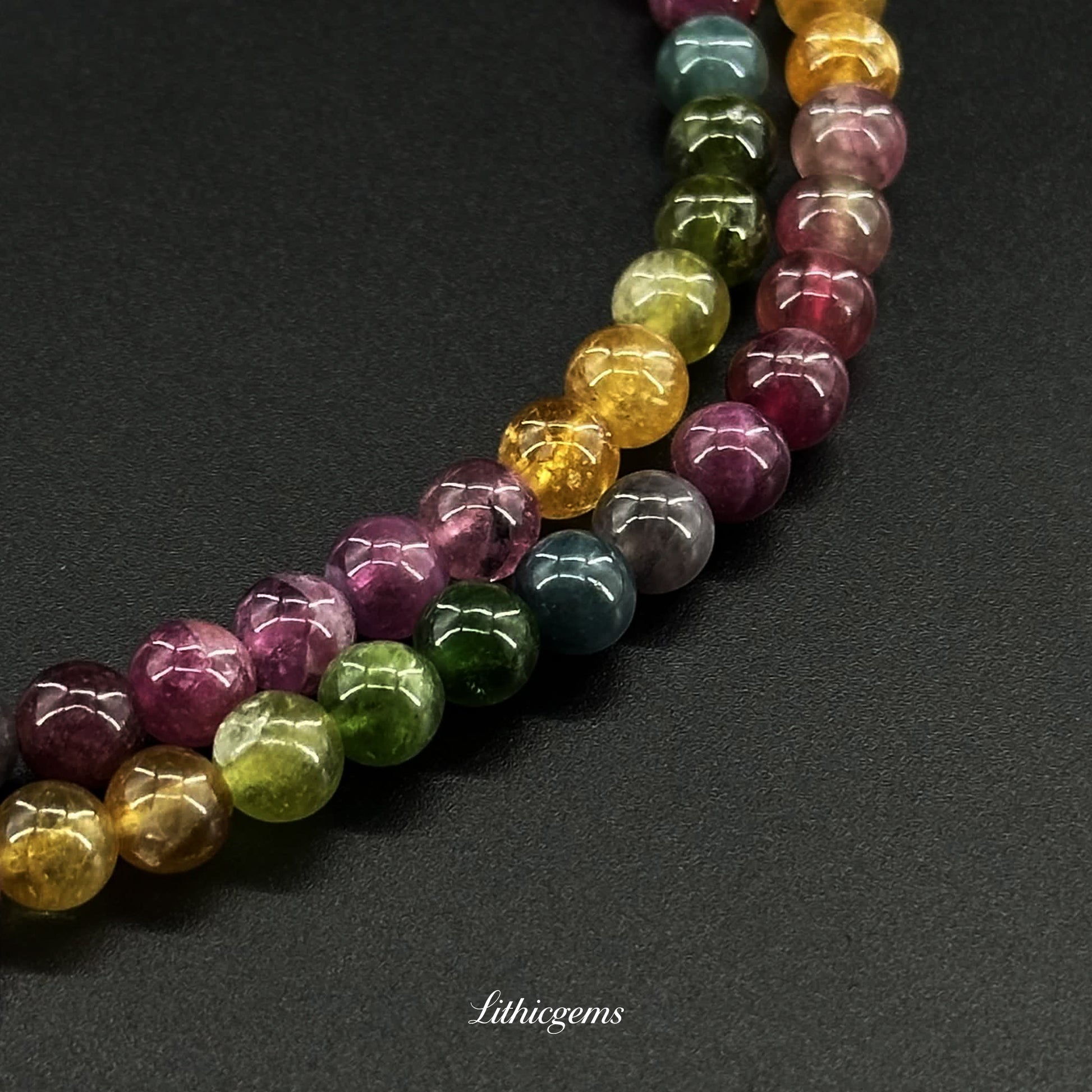 Close-up of polished multicolored natural gemstone beads on black background from Lithicgems